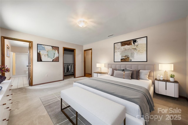 bedroom with visible vents, a spacious closet, light carpet, connected bathroom, and baseboards