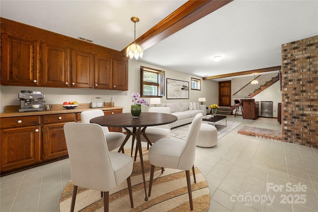 dining area featuring beam ceiling, light tile patterned floors, visible vents, stairway, and a textured ceiling