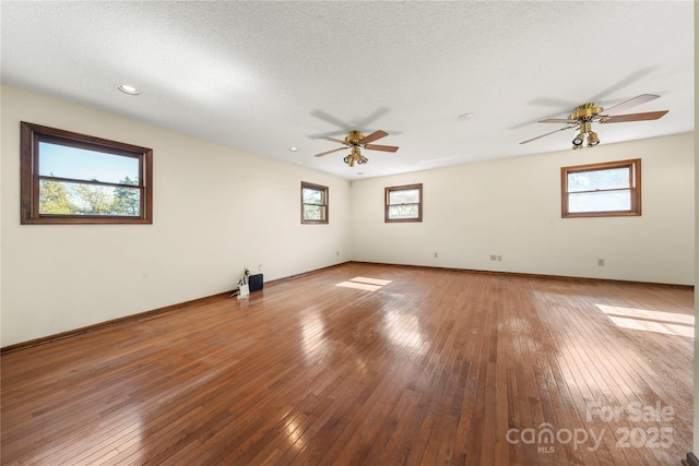 spare room featuring a ceiling fan, baseboards, light wood-style flooring, and a textured ceiling