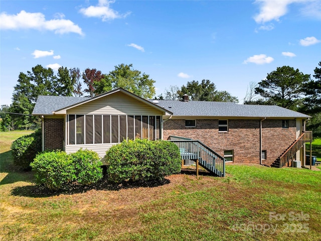 back of house featuring a sunroom, a chimney, stairway, a yard, and brick siding