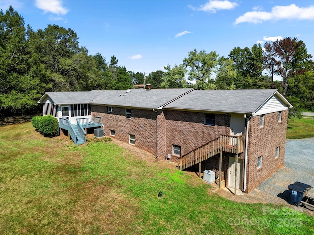 rear view of house with a wooden deck, a sunroom, stairs, a yard, and brick siding