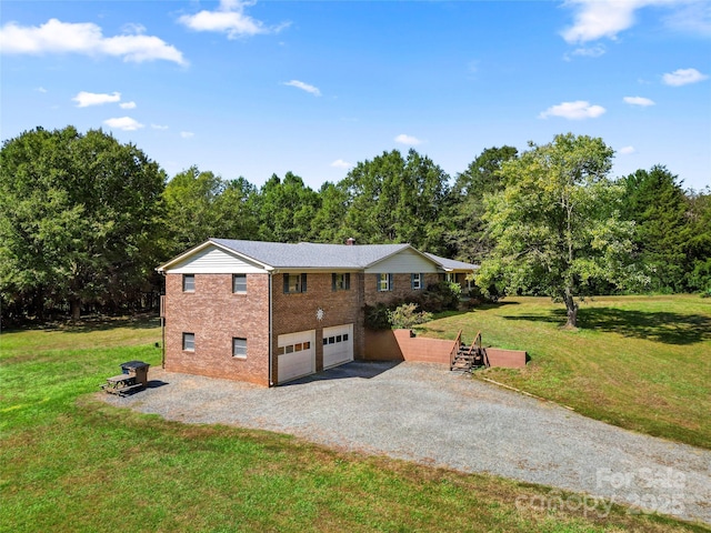 view of front facade with an attached garage, brick siding, a front lawn, and gravel driveway