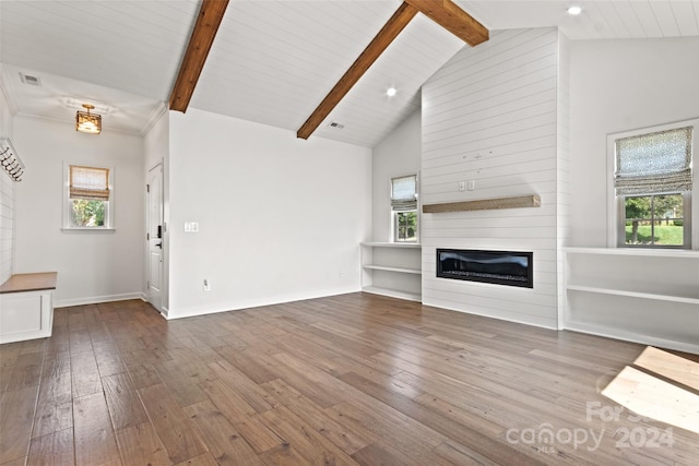 unfurnished living room featuring a fireplace, beamed ceiling, a healthy amount of sunlight, and hardwood / wood-style floors