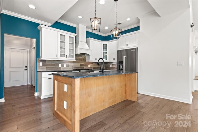 kitchen featuring a center island with sink, white cabinetry, dark wood-type flooring, high quality fridge, and custom exhaust hood