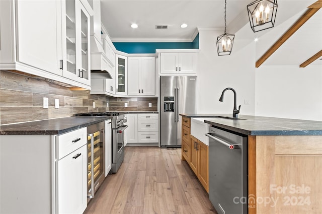 kitchen featuring light hardwood / wood-style flooring, white cabinetry, decorative light fixtures, and stainless steel appliances