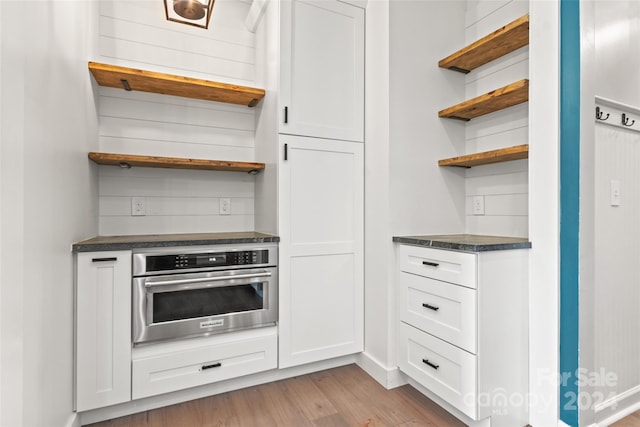 kitchen featuring white cabinetry, light hardwood / wood-style flooring, and oven