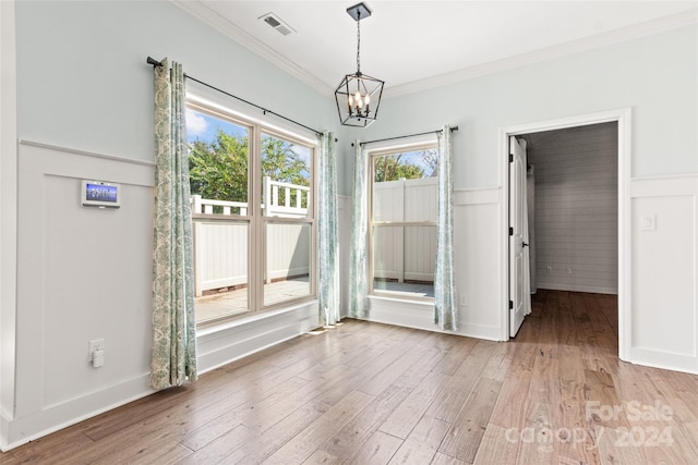 empty room with wood-type flooring, a chandelier, and ornamental molding