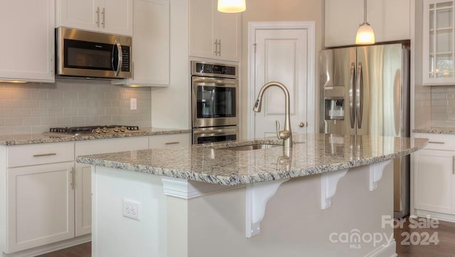 kitchen featuring appliances with stainless steel finishes, pendant lighting, and an island with sink