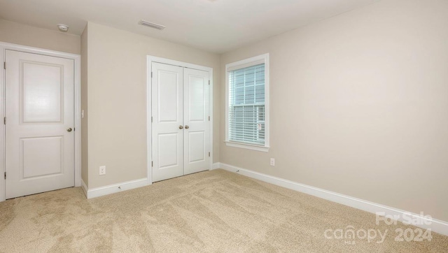 unfurnished bedroom with a closet and light carpet