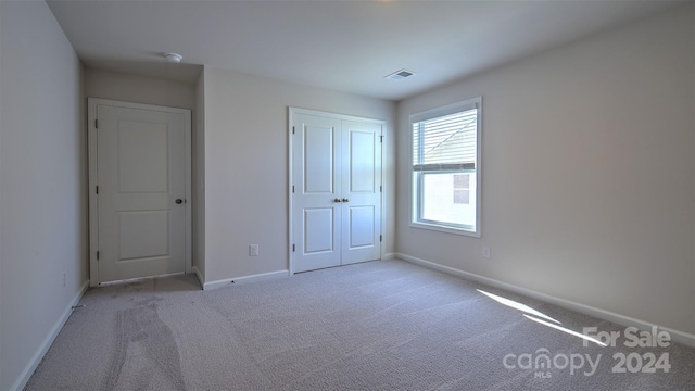 unfurnished bedroom featuring a closet and light carpet