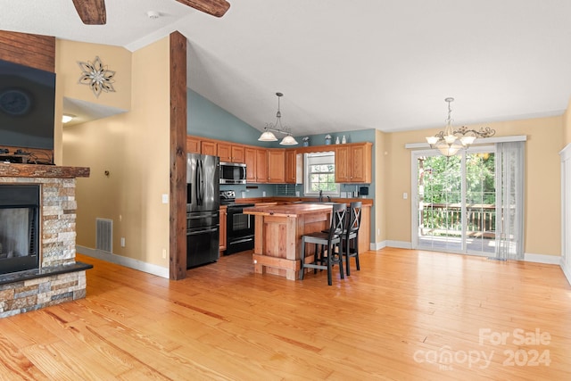 kitchen with stainless steel appliances, butcher block countertops, a stone fireplace, a kitchen breakfast bar, and a kitchen island