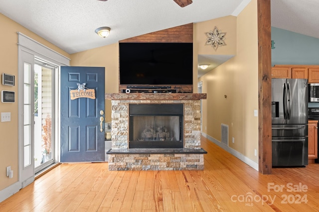 living room with lofted ceiling, a wealth of natural light, a fireplace, and light hardwood / wood-style floors