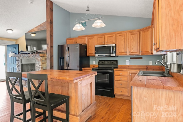 kitchen featuring light wood-type flooring, a kitchen island, stainless steel appliances, and wood counters