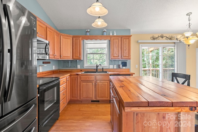 kitchen featuring a center island, appliances with stainless steel finishes, wood counters, and sink