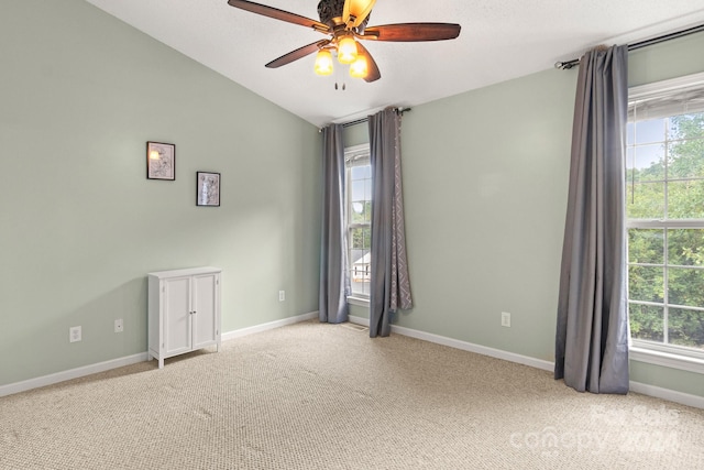 empty room with lofted ceiling, ceiling fan, and light carpet