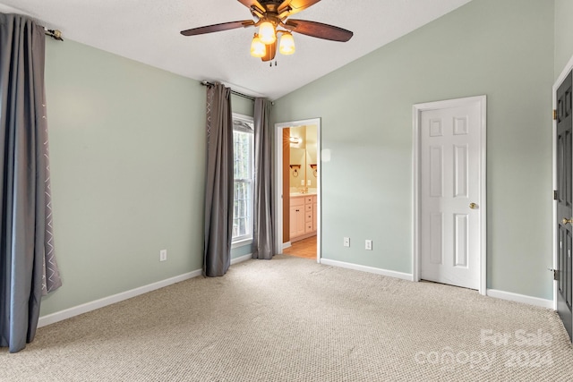 interior space featuring light colored carpet, lofted ceiling, connected bathroom, and ceiling fan