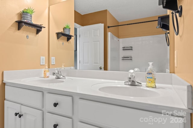 bathroom featuring a textured ceiling, vanity, and a shower