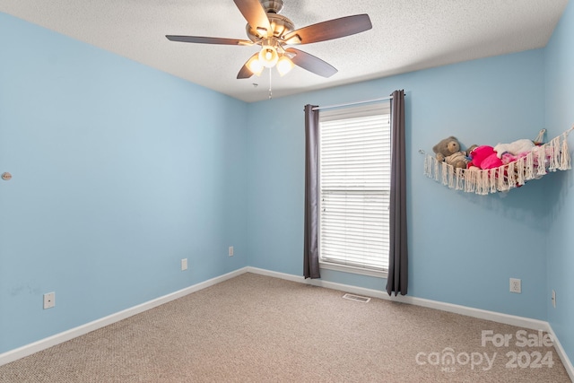 spare room with carpet flooring, ceiling fan, plenty of natural light, and a textured ceiling