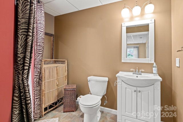 bathroom featuring vanity, toilet, and a drop ceiling