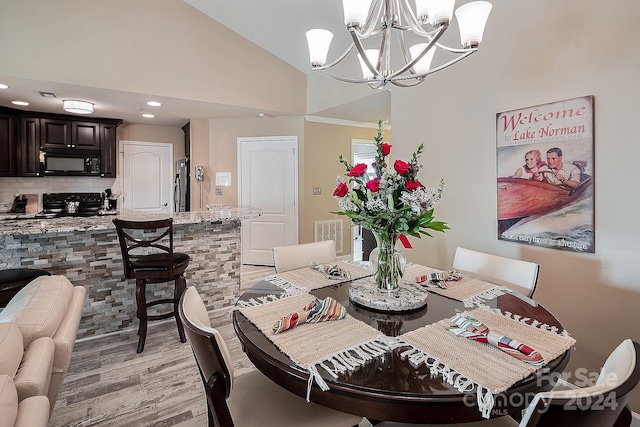 dining area with light hardwood / wood-style flooring, a notable chandelier, and vaulted ceiling