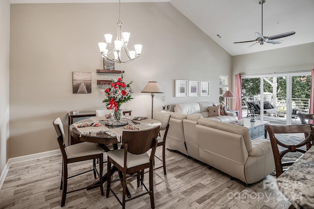 dining space featuring ceiling fan with notable chandelier, high vaulted ceiling, and light hardwood / wood-style floors