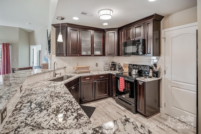 kitchen with light hardwood / wood-style flooring, black appliances, sink, light stone countertops, and hanging light fixtures