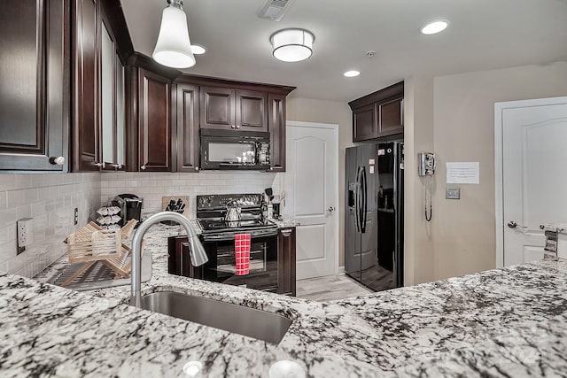 kitchen featuring light stone countertops, dark brown cabinets, black appliances, tasteful backsplash, and sink