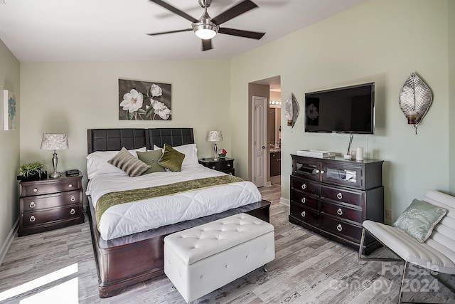 bedroom featuring ceiling fan, vaulted ceiling, connected bathroom, and light hardwood / wood-style flooring