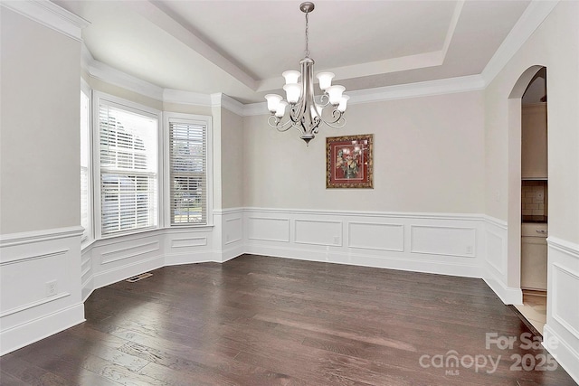 unfurnished dining area with a raised ceiling, dark wood-type flooring, and a chandelier