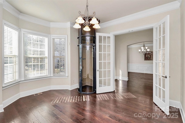 unfurnished dining area featuring ornamental molding, dark hardwood / wood-style floors, an inviting chandelier, and french doors