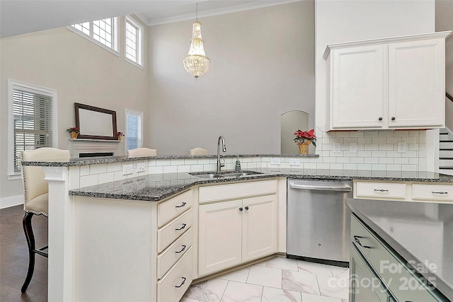 kitchen featuring sink, tasteful backsplash, kitchen peninsula, pendant lighting, and white cabinets