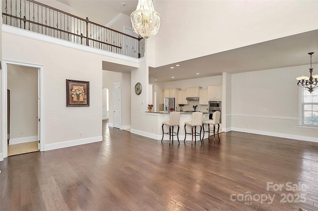 living room featuring a high ceiling, dark wood-type flooring, and a chandelier