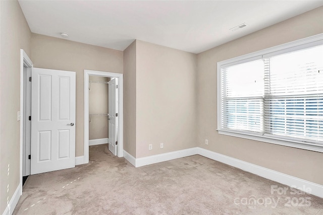 unfurnished bedroom with multiple windows, light colored carpet, and a closet