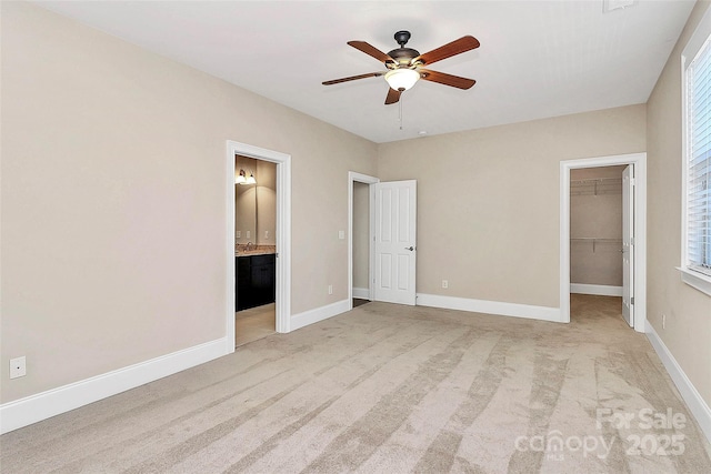 unfurnished bedroom with connected bathroom, a spacious closet, ceiling fan, light carpet, and a closet