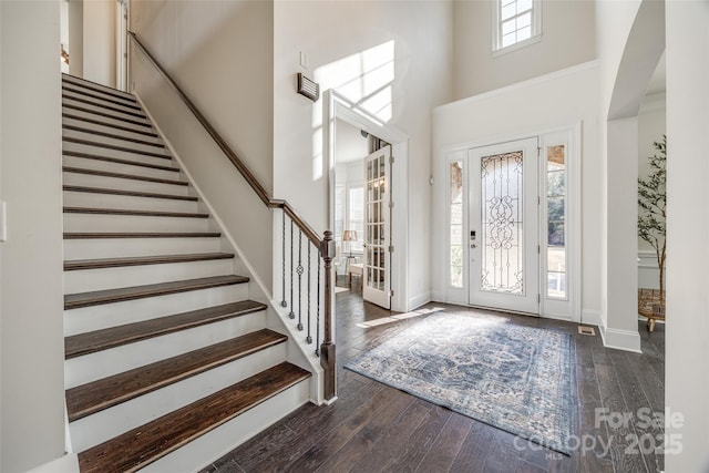 foyer featuring dark wood-type flooring, baseboards, a high ceiling, and stairs