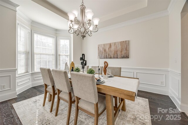 dining area with ornamental molding, dark wood-type flooring, an inviting chandelier, and a decorative wall