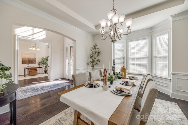 dining area with arched walkways, dark wood-style flooring, a notable chandelier, a decorative wall, and ornamental molding