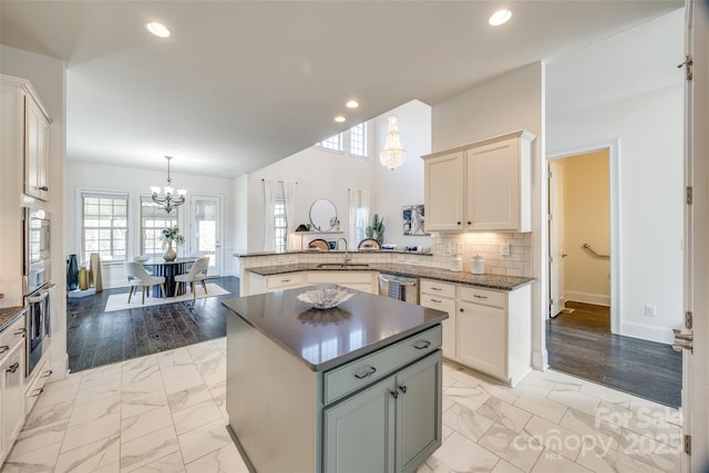 kitchen with a chandelier, marble finish floor, a sink, and a peninsula