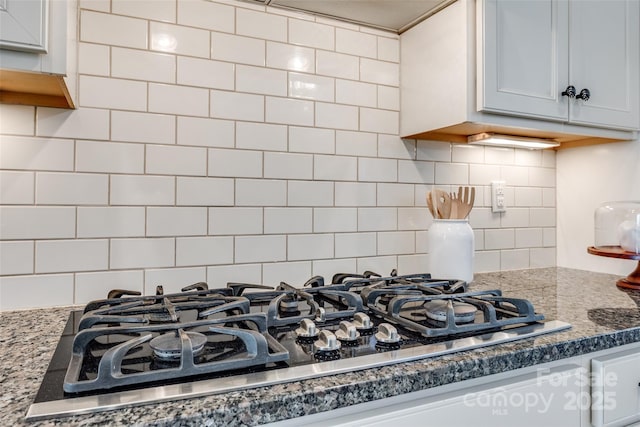 room details featuring black gas stovetop, backsplash, and light stone countertops