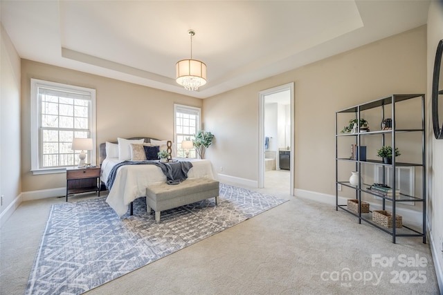 carpeted bedroom with a tray ceiling, multiple windows, and baseboards