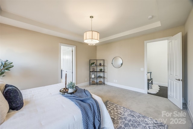 bedroom featuring a chandelier, carpet floors, a tray ceiling, and baseboards