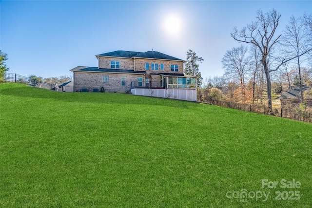 back of property featuring fence, a lawn, and brick siding