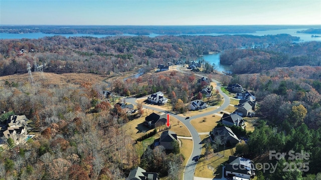 birds eye view of property with a water view and a wooded view