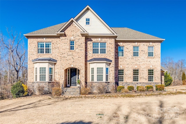 view of front of house with a shingled roof and brick siding