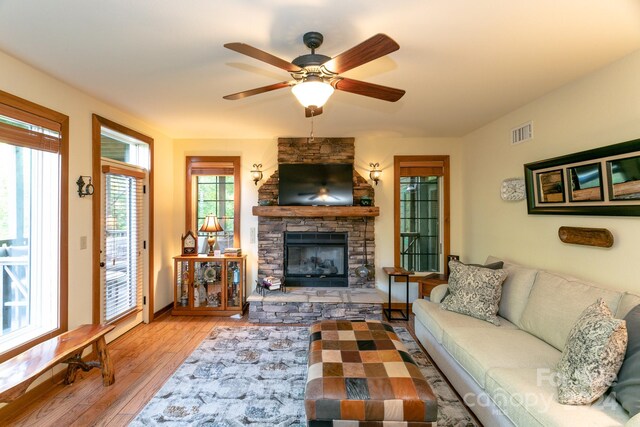 living room with a stone fireplace, ceiling fan, and hardwood / wood-style floors