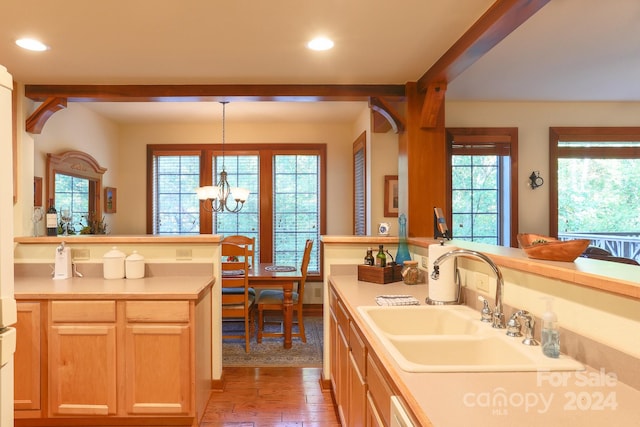 kitchen with light hardwood / wood-style flooring, kitchen peninsula, a notable chandelier, and decorative light fixtures