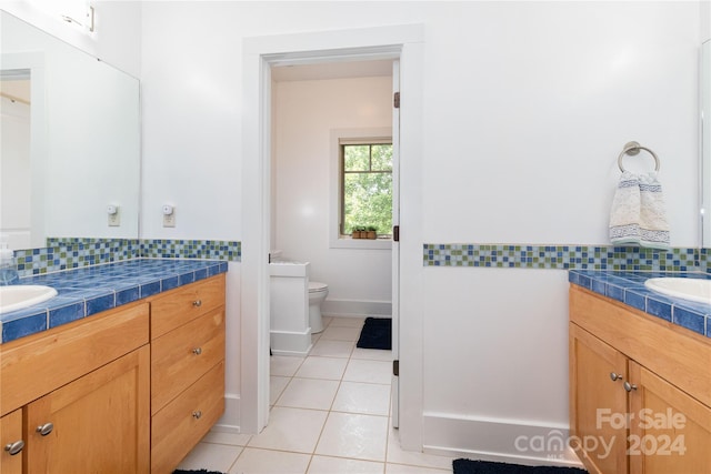 bathroom with tile patterned floors, toilet, decorative backsplash, and vanity