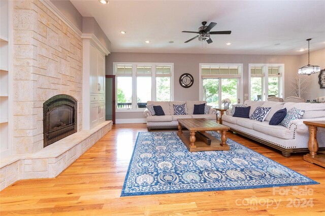 living room with ceiling fan, a fireplace, plenty of natural light, and light hardwood / wood-style flooring