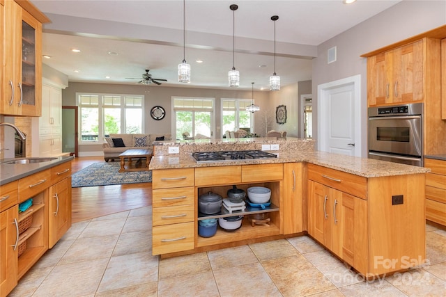 kitchen featuring ceiling fan, a wealth of natural light, a center island, and sink