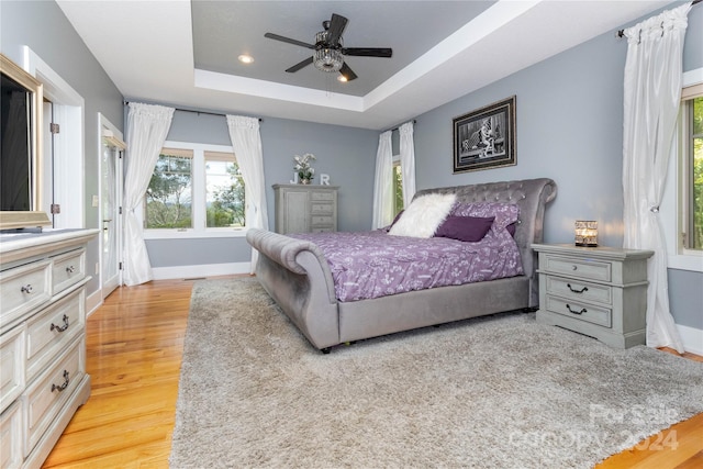 bedroom with a tray ceiling, ceiling fan, and light hardwood / wood-style floors